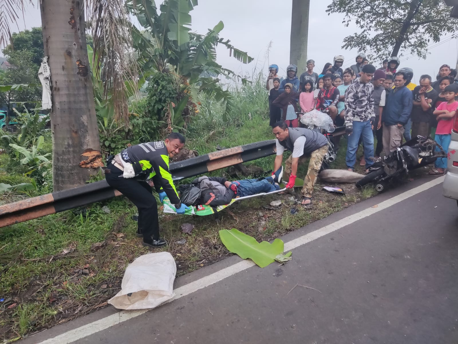 KECELAKAAN: Anggota Lantas Polsek Tanjungsari dan petugas Puskesmas Tanjungsari saat mengevakuasi korban kecelakaan ditikungan Sanur Tanjungsari (for Radar Sumedang).