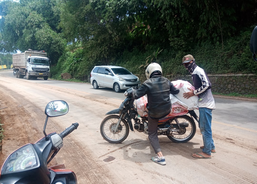 PENGENDARA: Salah seorang pengendara seusai terjatuh didepan galian tunggul Hideung karena jalan licin akibat lumpur.